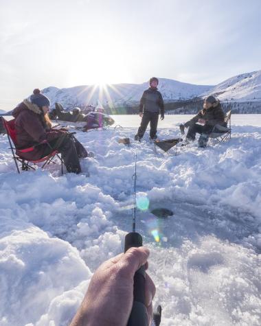 A group of people ice fishing on a Yukon lake