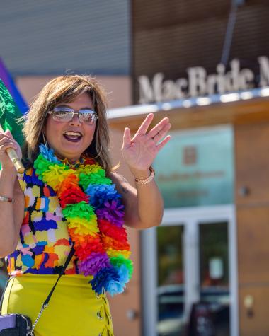A woman wearing a rainbow necklace walking in a pride parade