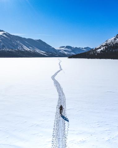 Fat biker on a large snow-covered frozen lake surrounded by mountains