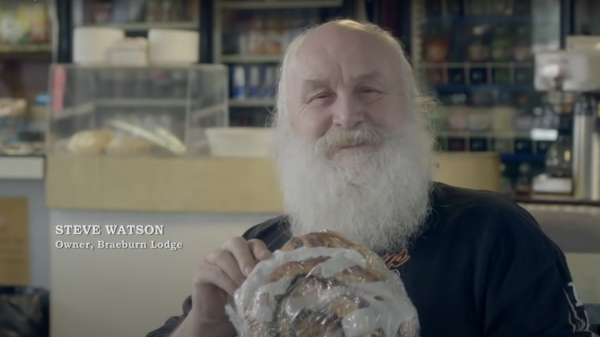 The owner of Braeburn lodge sits with a large cinnamon bun