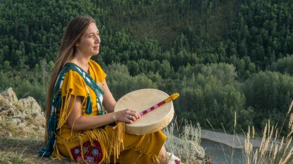 A Trondek Hwechin dancer overlooks a river