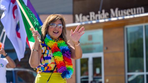 A woman wearing a rainbow necklace walking in a pride parade