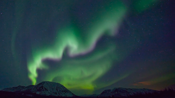 Swirly green and purple aurora above a mountain