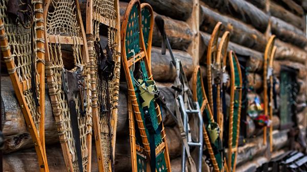 Snowshoes leaning against a log cabin