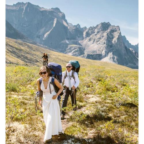 A newly wedded couple hikes through Tombstone Territorial Park, in their wedding dress and suit.