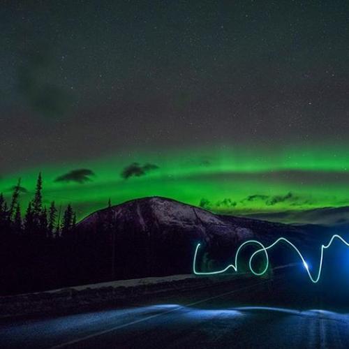 A person writes love as the northern lights shine in the background
