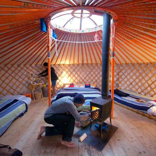 A person lights a wood stove inside a cozy yurt in the Yukon.