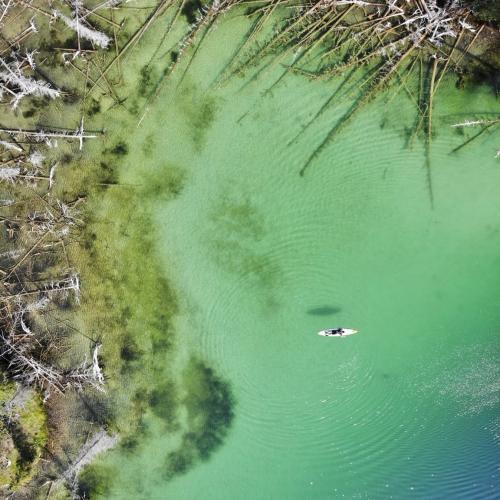 A paddle boarder floats across teal water