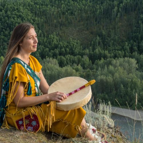 A Trondek Hwechin dancer overlooks a river