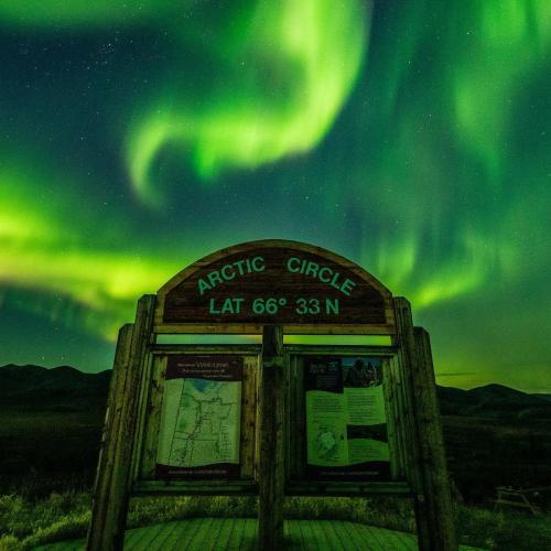 Arctic circle sign under northern lights