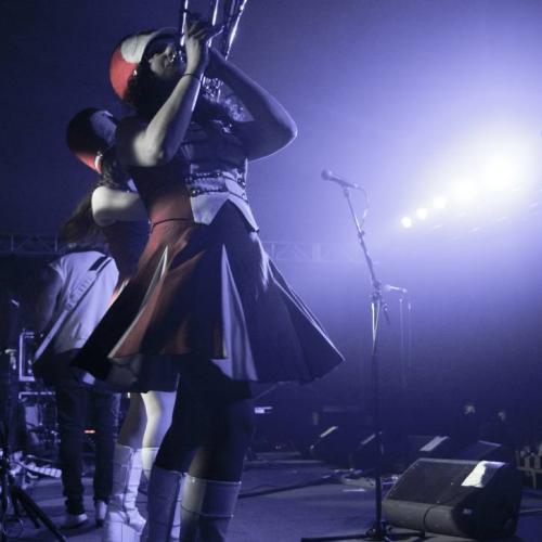 Person playing trumpet in a large hat and dress