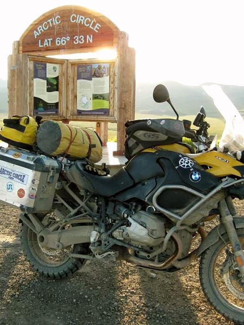 A motorcycle sits in front of the Arctic Circle sign