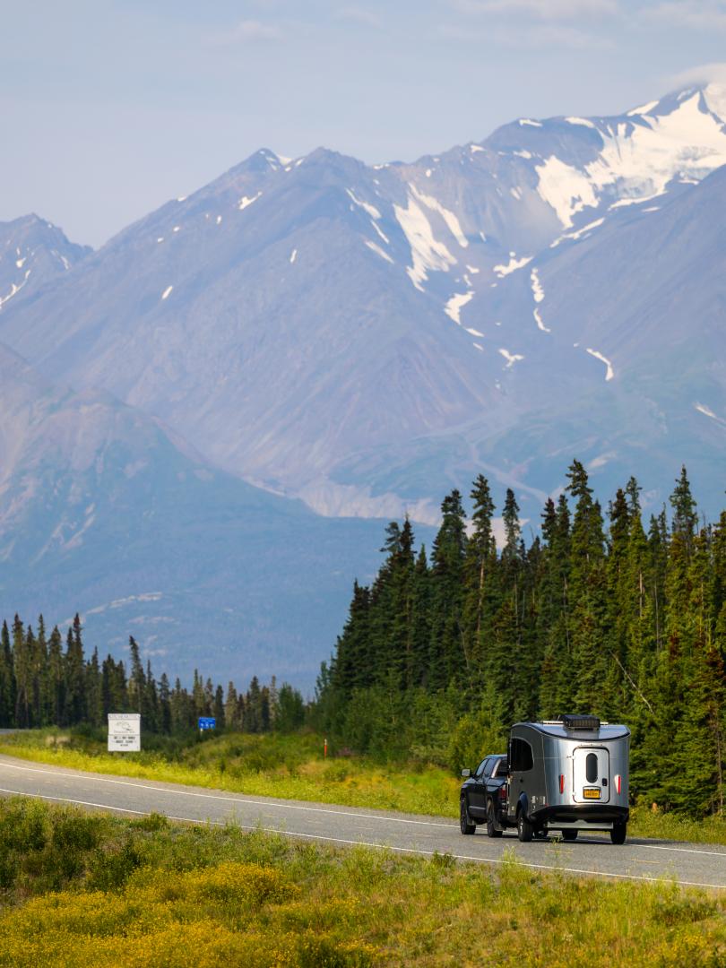 An RV driving east along the Alaska Highway into Haines Junction, towards Mount Archibald.