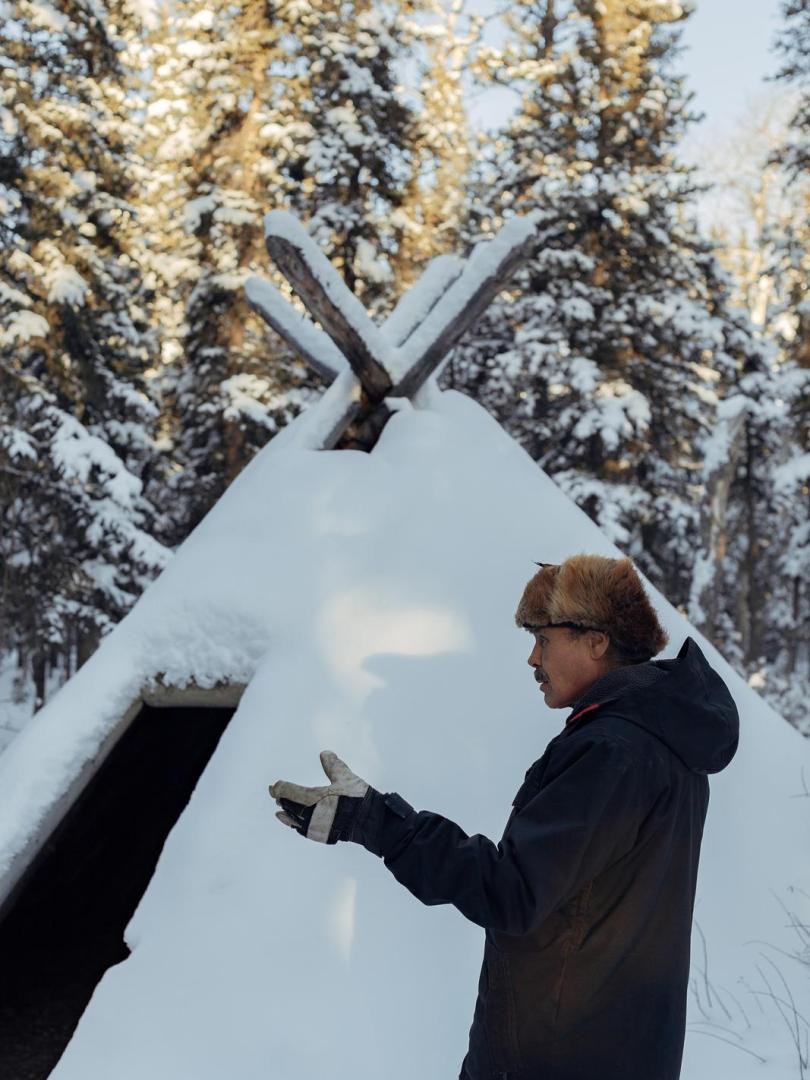 man standing outside a first nation hut