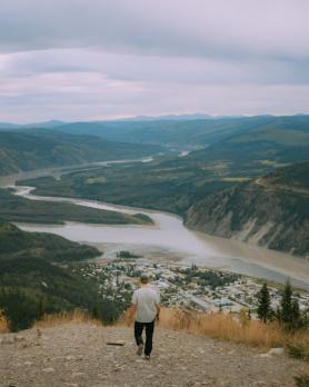 Man walking down a trail above a small town