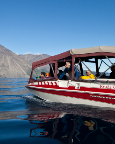 A red power boat on a big lake with a mountain in the background