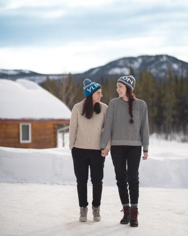 A couple stands in the snow in front of a lodge