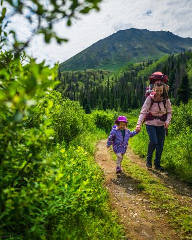 A family hiking on the St. Elias Trail in Kluane National Park and Reserve. The peak behind them is called Tl’eheda, which means “tent” in the Southern Tutchone language.