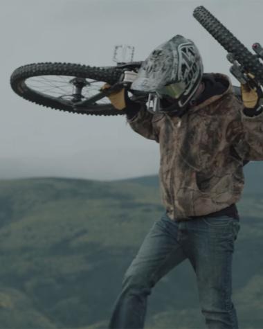 A man lifts his mountain bike above his shoulders
